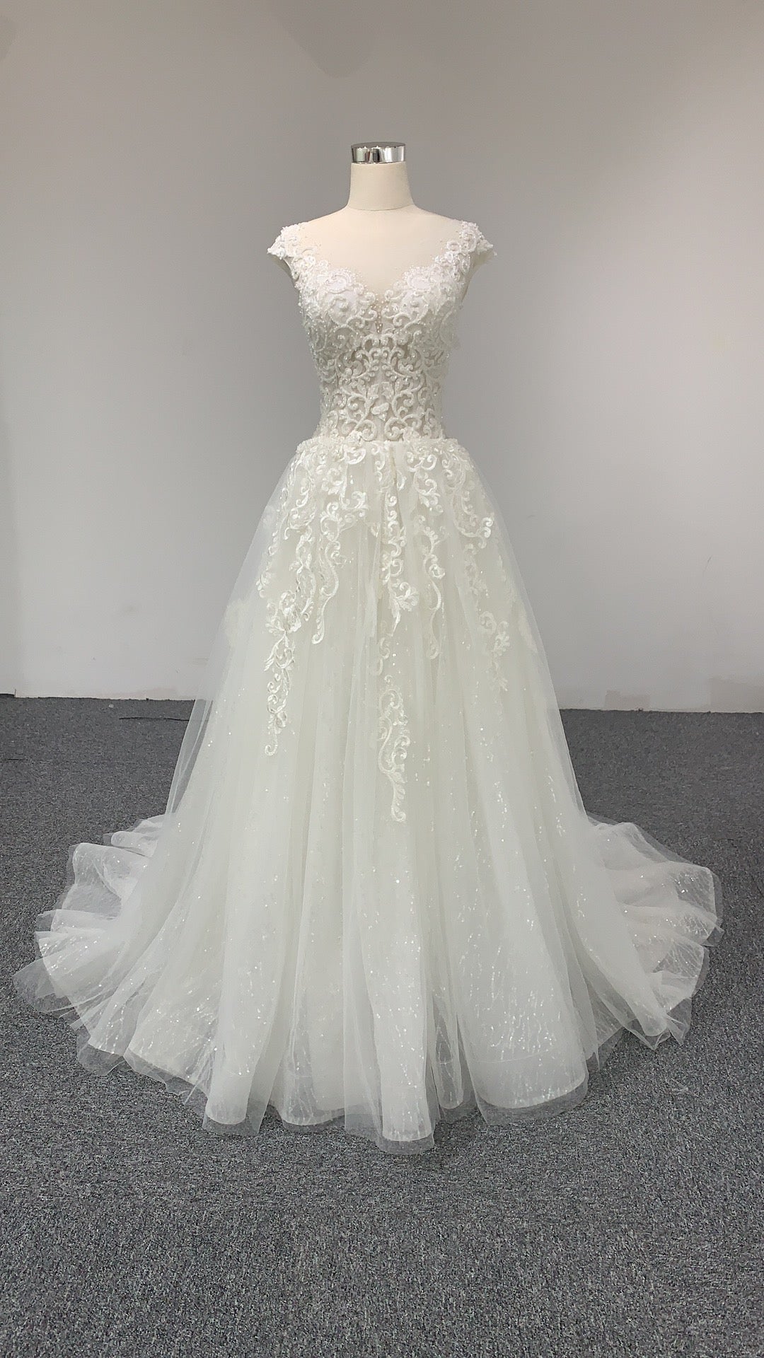 A V-neck A-line lace wedding dress with a court train and cap sleeves.