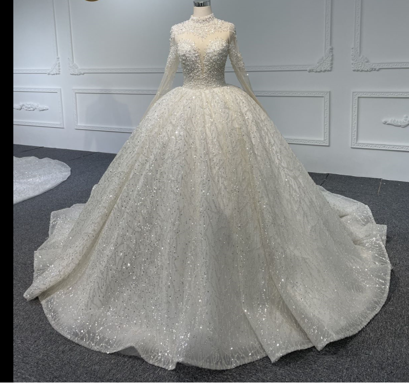A luxurious long-sleeved white ball gown with crystal and pearls beading, a train, and back strap. A luxurious long-sleeved white ball gown with crystal and pearls beading, a train, and back strap.