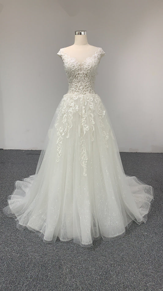 A V-neck A-line lace wedding dress with a court train and cap sleeves.