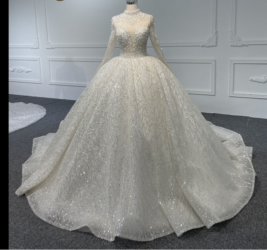 A luxurious long-sleeved white ball gown with crystal and pearls beading, a train, and back strap.
