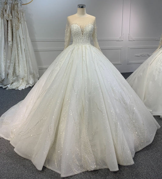 A white ball gown with long sleeves and a sweetheart neckline, featuring beading and lace details.
